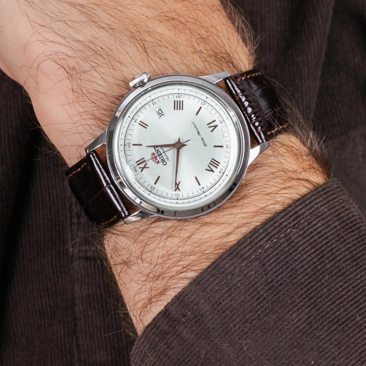 Men's automatic leather watch on wrist: white dial with Roman numerals, brown leather strap