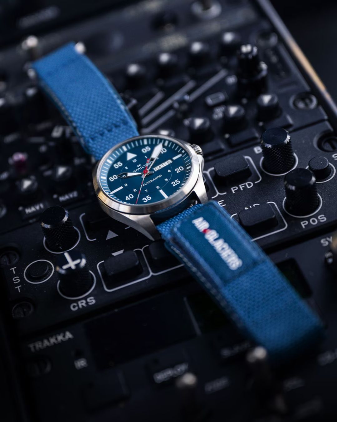 Hamilton Khaki Aviation Pilot watch with blue dial and Air Glaciers blue fabric strap on airplane cockpit controls