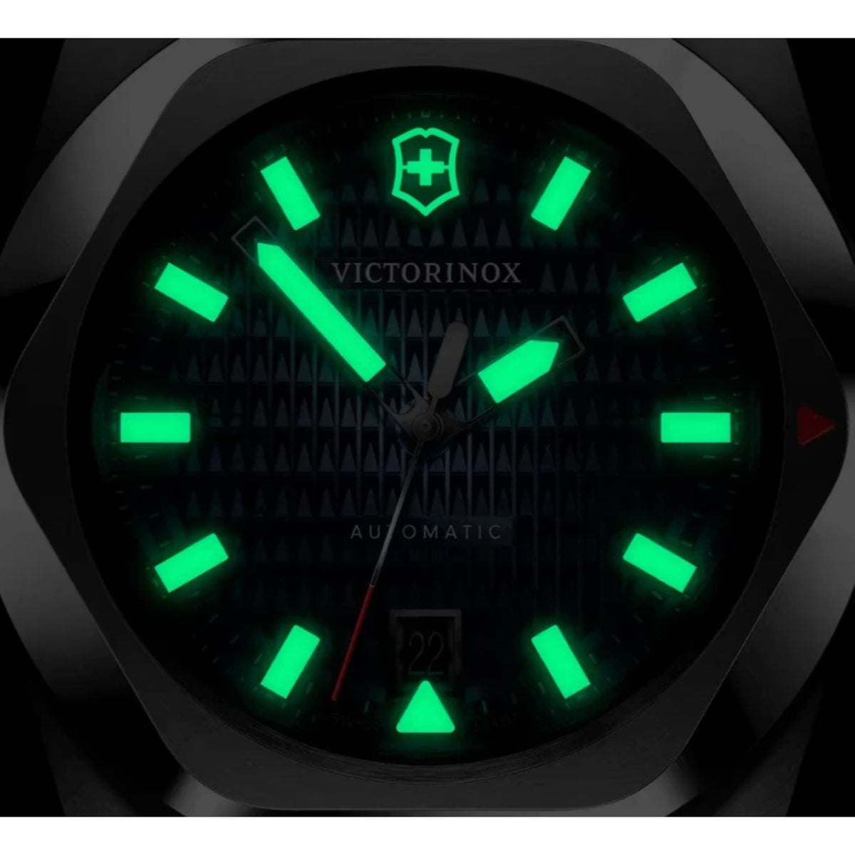 A dark close-up shot of a Victorinox watch featuring green glowing lume 