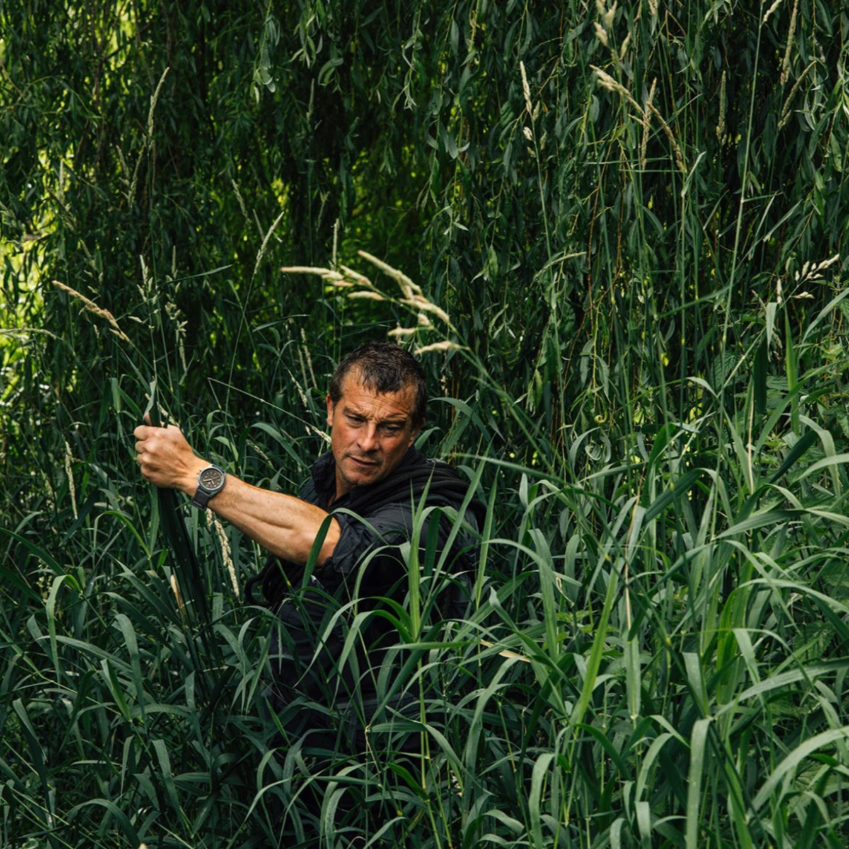 Close shot of Bear Grylls pushing through thick brush wearing the grey Luminox Bear Grylls Survival XB.3716 quartz watch