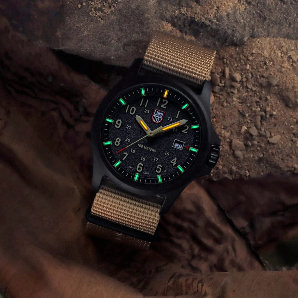 Black quartz field watch with tan fabric strap and green luminous dial markers