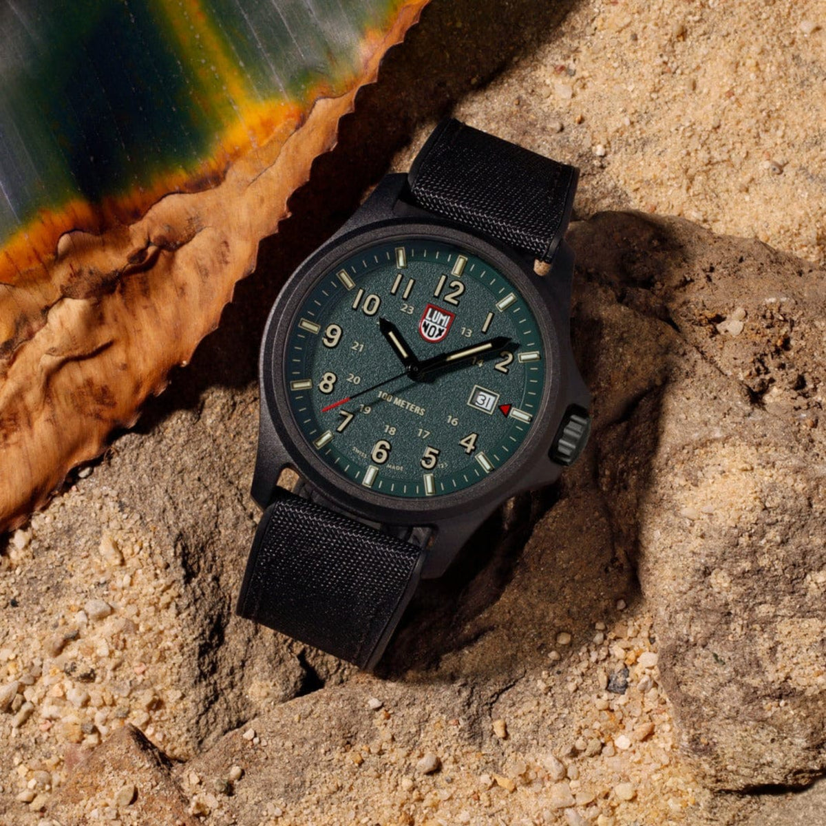 Luminox Atacama Field XL.1977 tactical watch resting on desert sand and rock terrain.