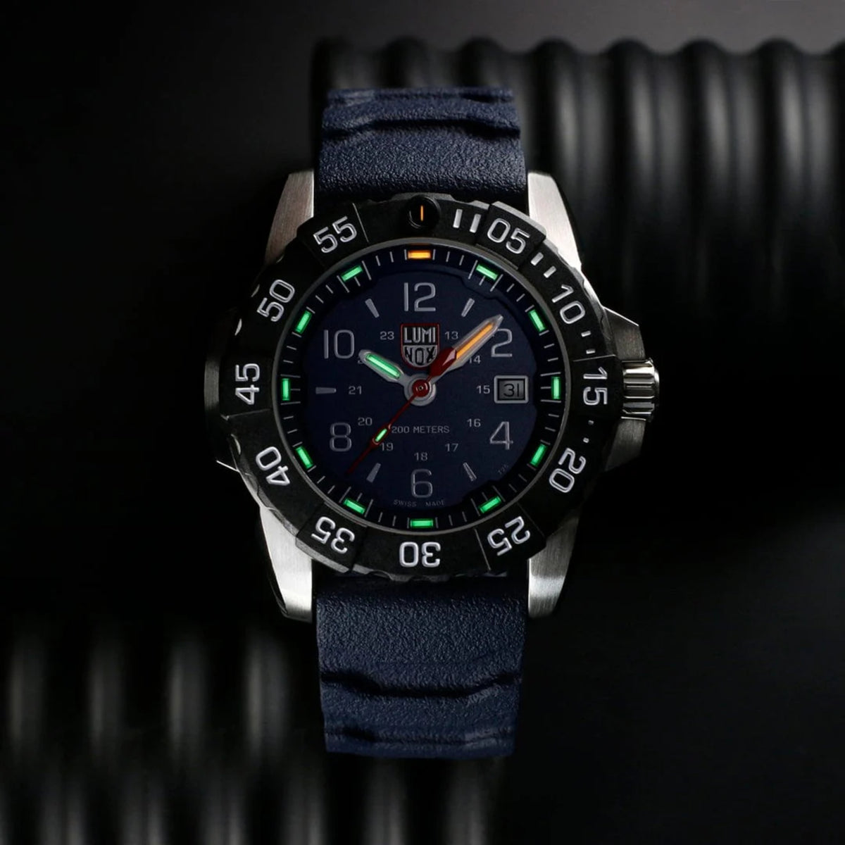 Dark dial quartz watch with luminous green markers on navy fabric-textured strap