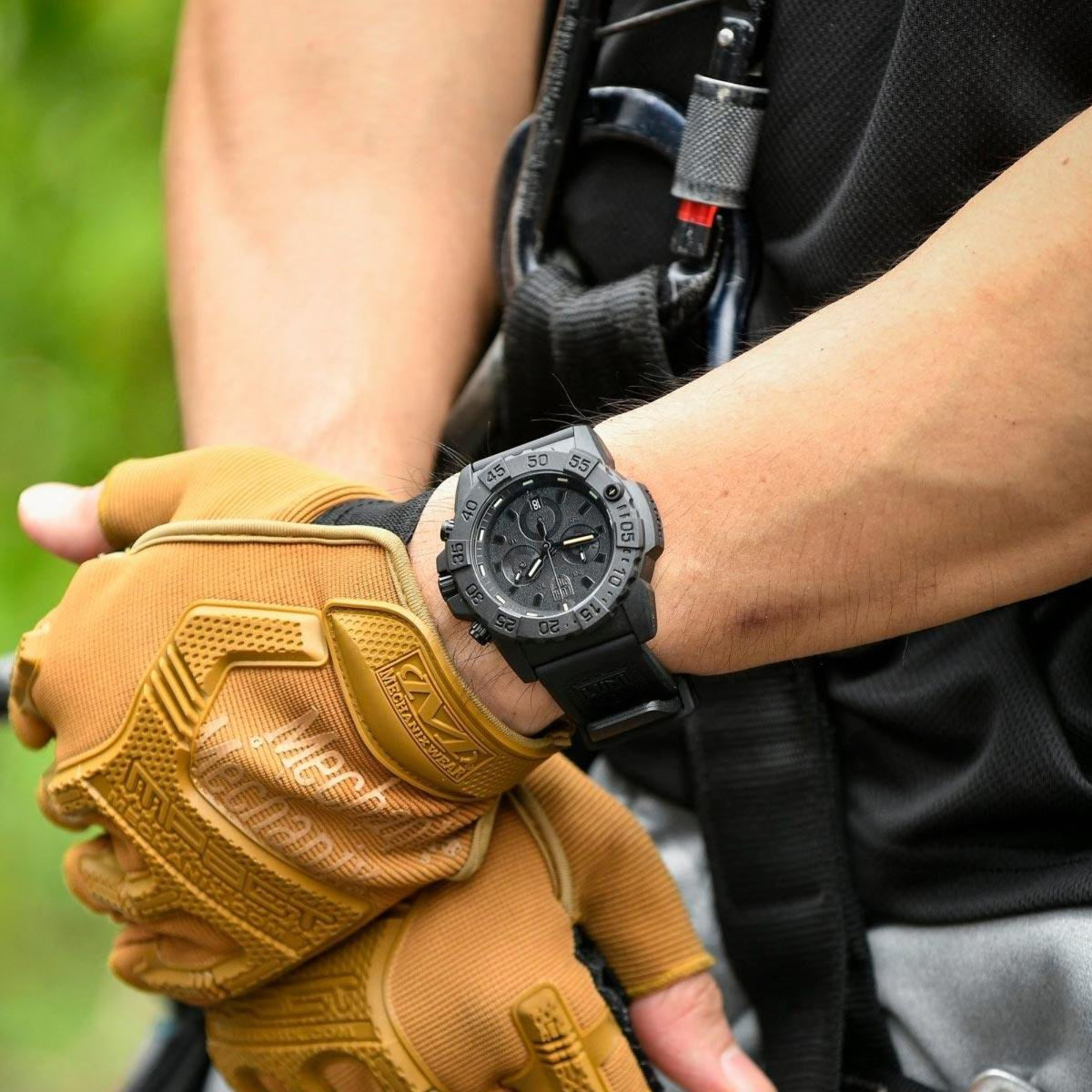 Outdoor tactical wrist shot of the Luminox Navy SEAL XS.3581.BO chronograph paired with tan workout gloves and climbing gear