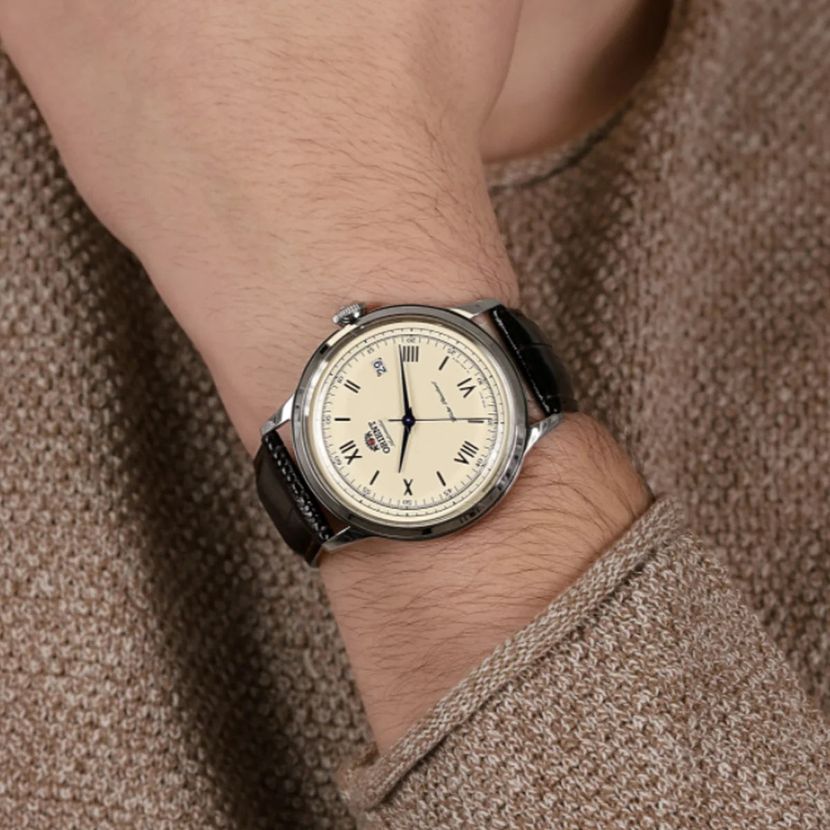 Orient Bambino TAC00009N0 automatic leather watch on wrist, dark strap and pale dial with Roman numerals
