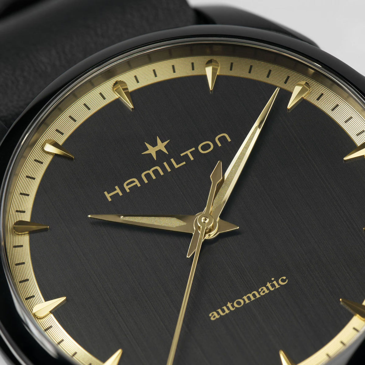 Close-up black dial automatic watch with gold hour markers, hands, and Hamilton text