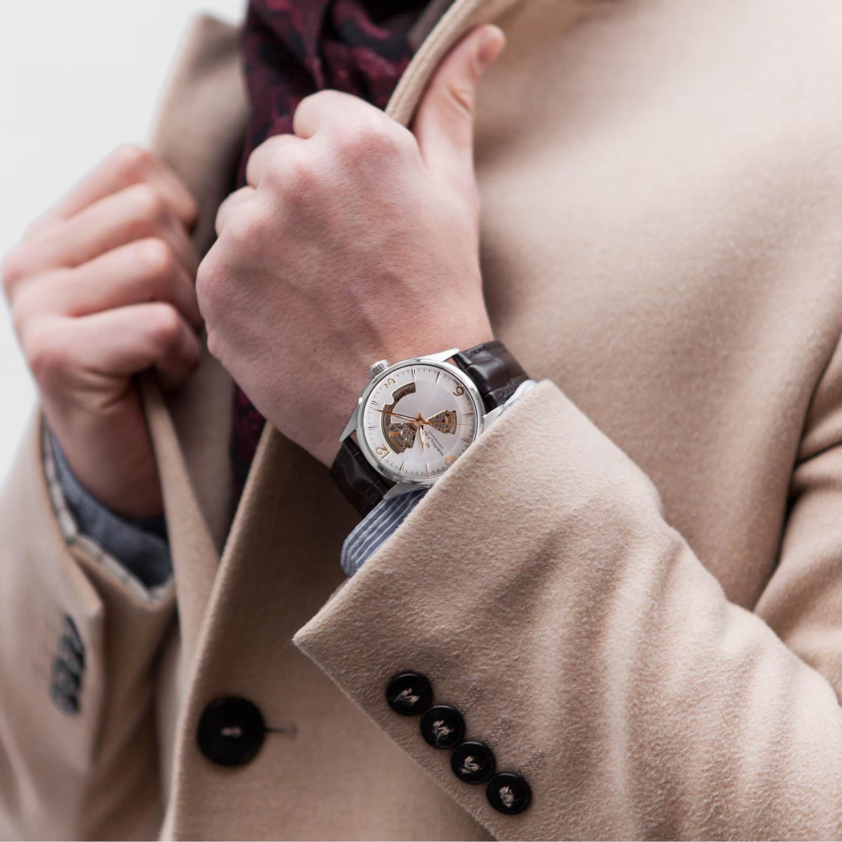 Automatic watch with silver case and brown leather strap worn on wrist