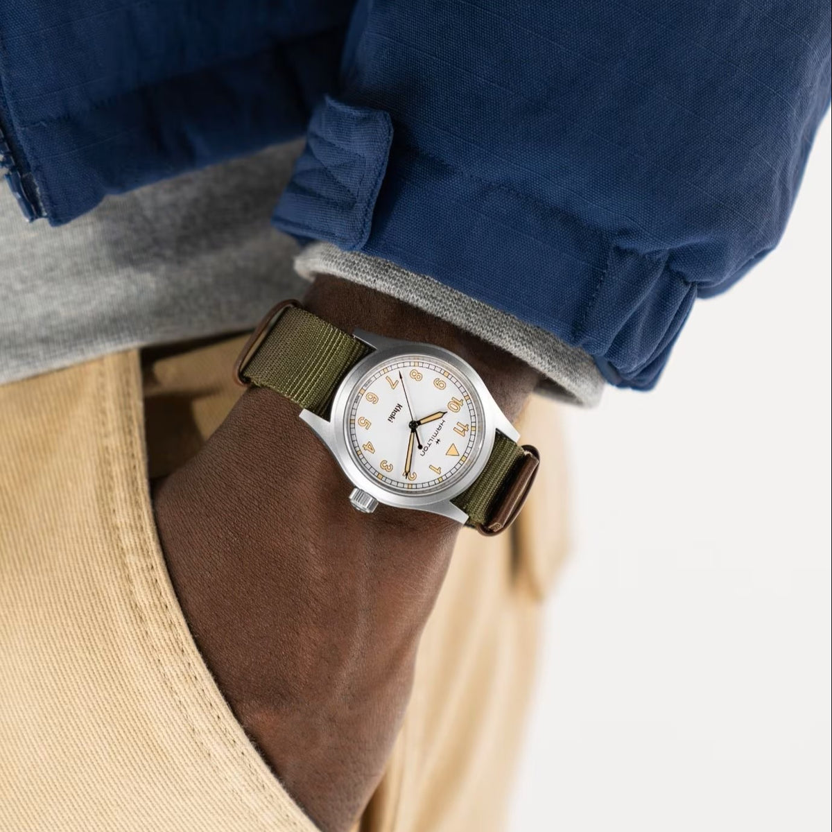Hamilton Khaki Field H69401910 quartz watch wrist shot styled with blue jacket showing white dial and green fabric band
