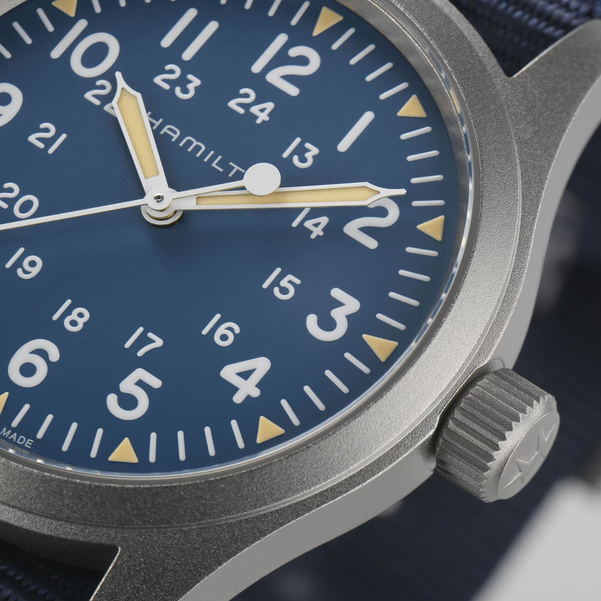 Macro view of Hamilton Khaki Field H69439940 featuring luminous hands, 24-hour inner track, and stainless steel case