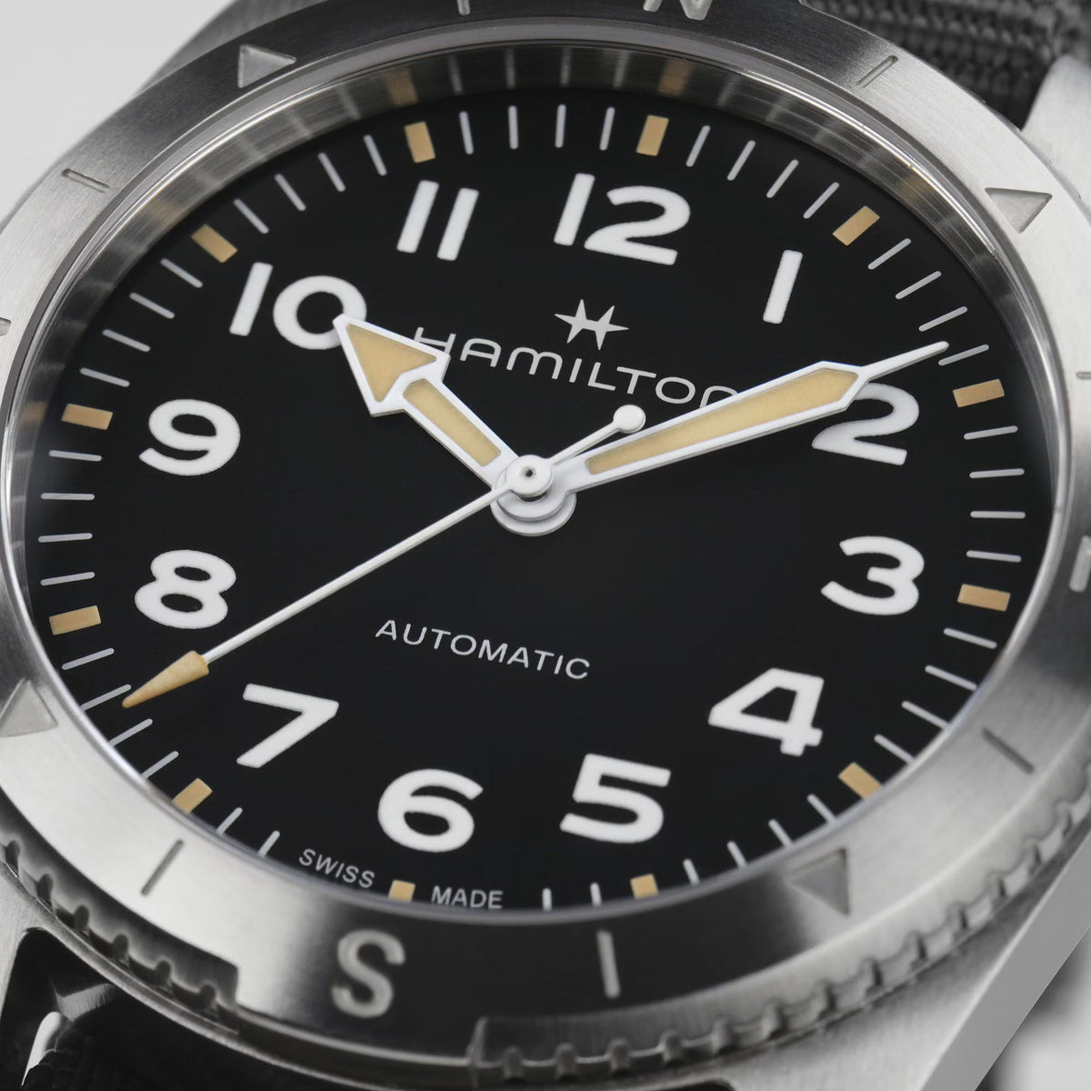 Close-up of black dial automatic watch with gold hands, star logo, and numeric markers
