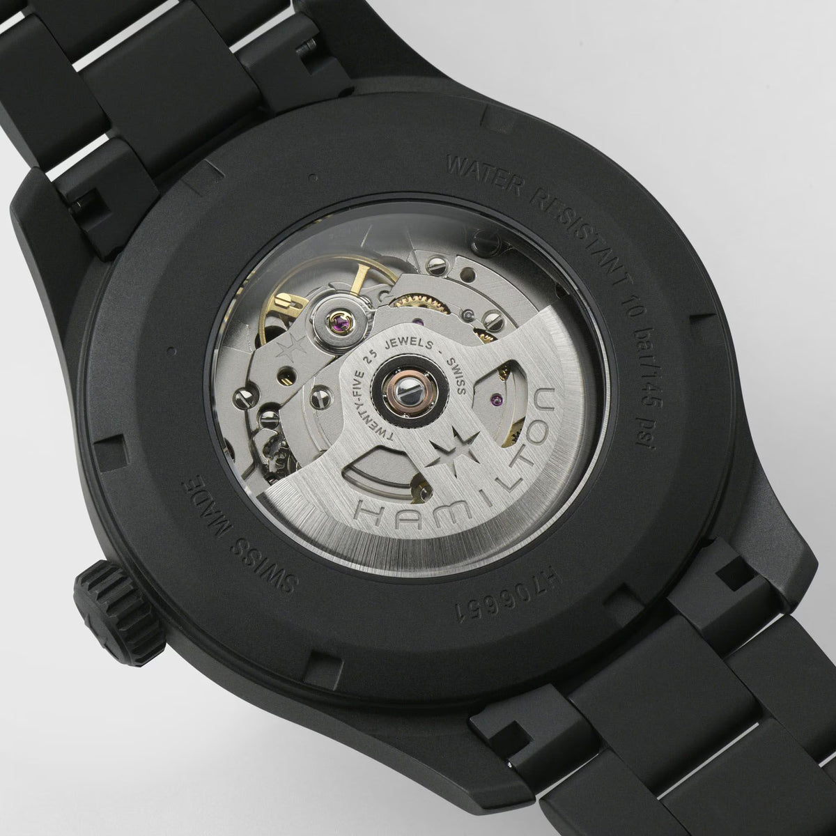 Black watch case back with visible automatic movement and black link bracelet