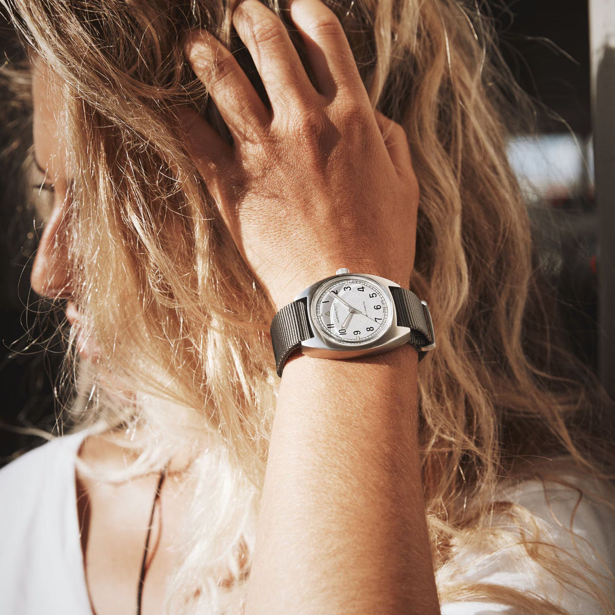 Hamilton Khaki Pilot Pioneer watch with a white dial and grey textile strap, on a wrist
