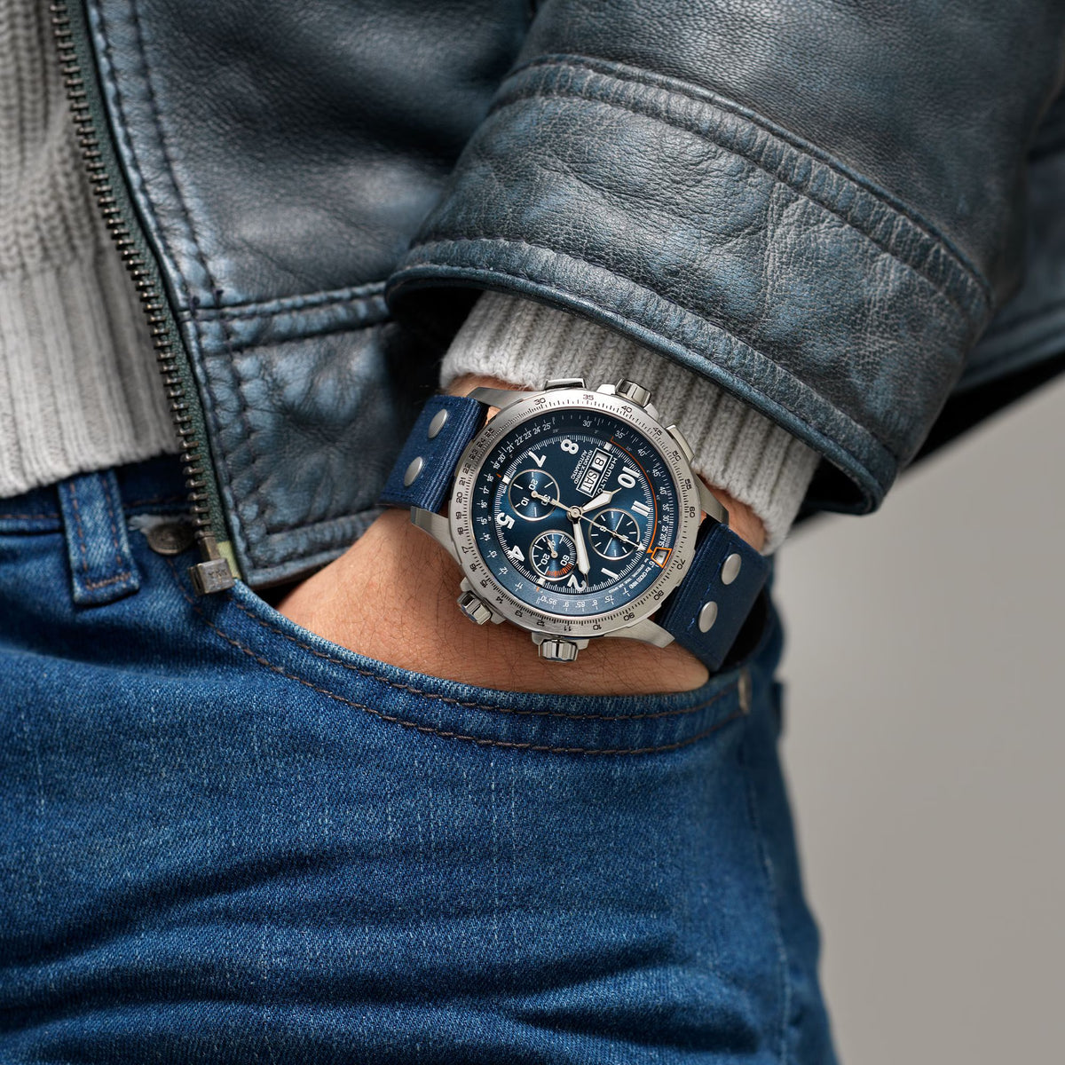 Men's chronograph watch on wrist with blue fabric strap and blue dial