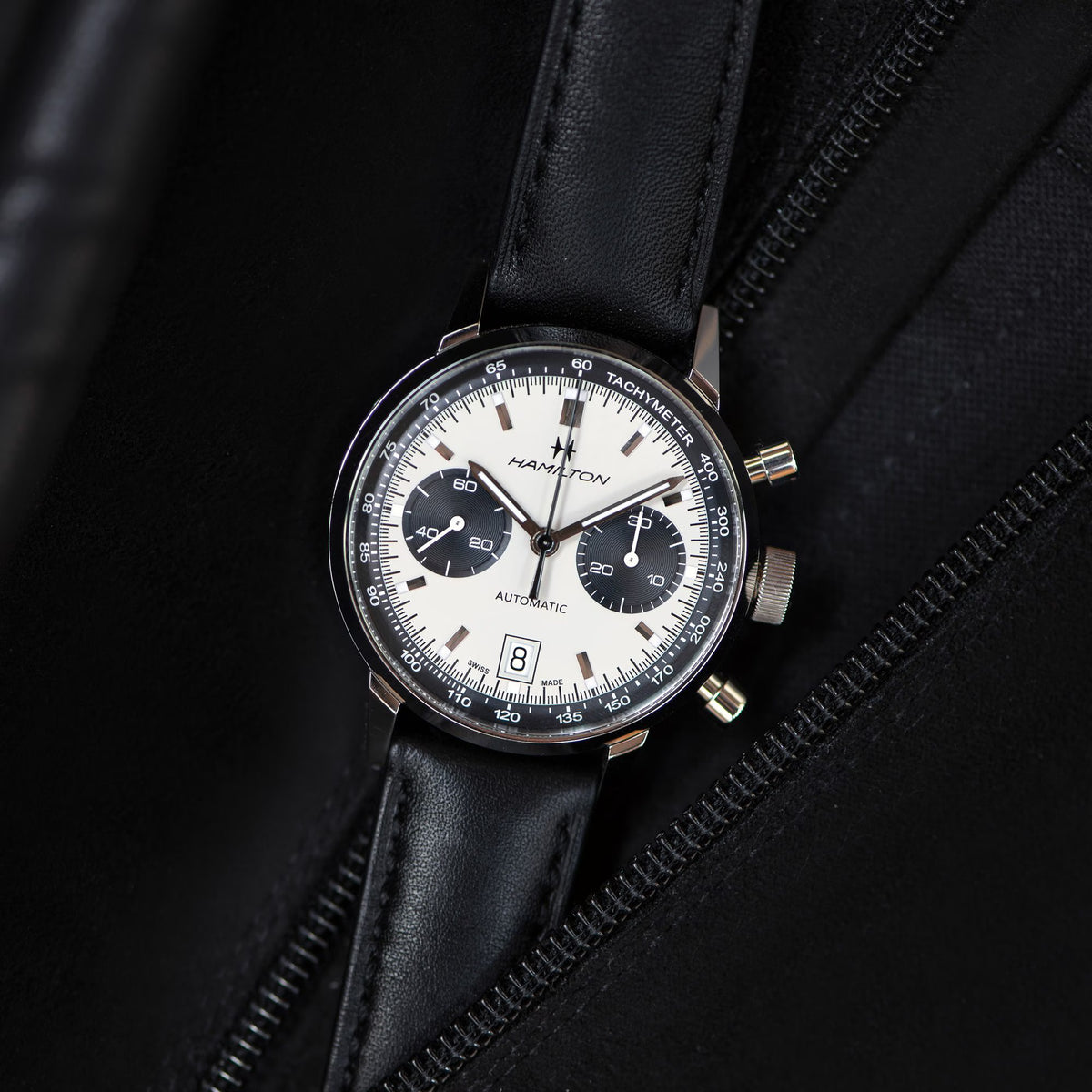 Hamilton Intra-Matic Auto Chrono watch with white panda dial and black leather strap shown against a black background