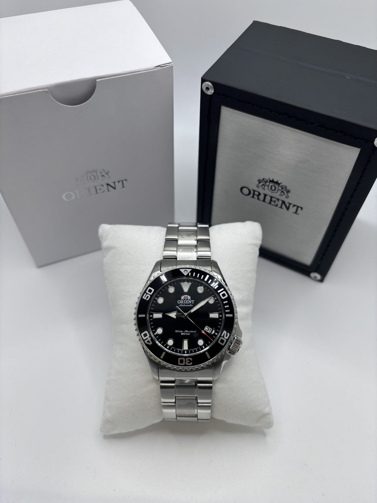 Automatic men's watch on white cushion, black dial with bezel markings, in gift box