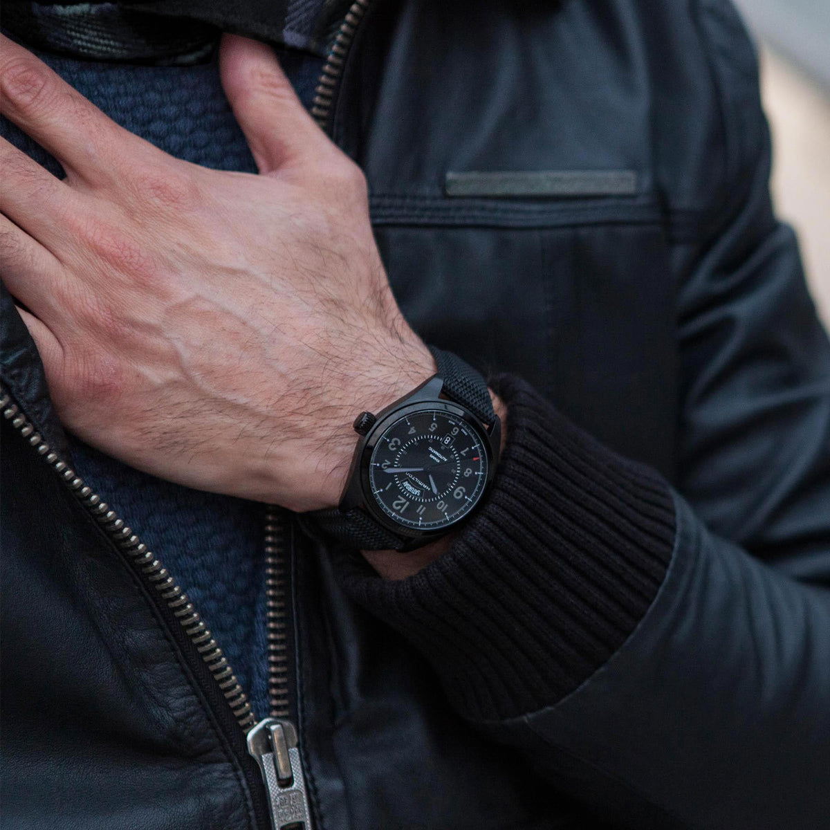 Men's automatic watch on wrist with black dial and textured black strap