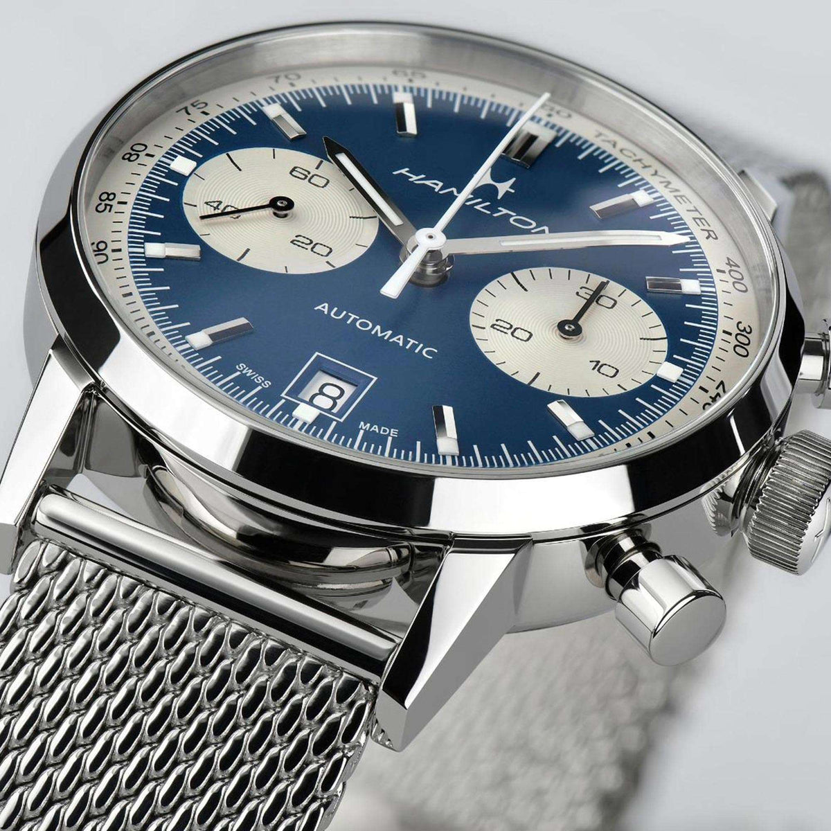 Chronograph watch dial in blue with date window, baton hands, and subdial at 20