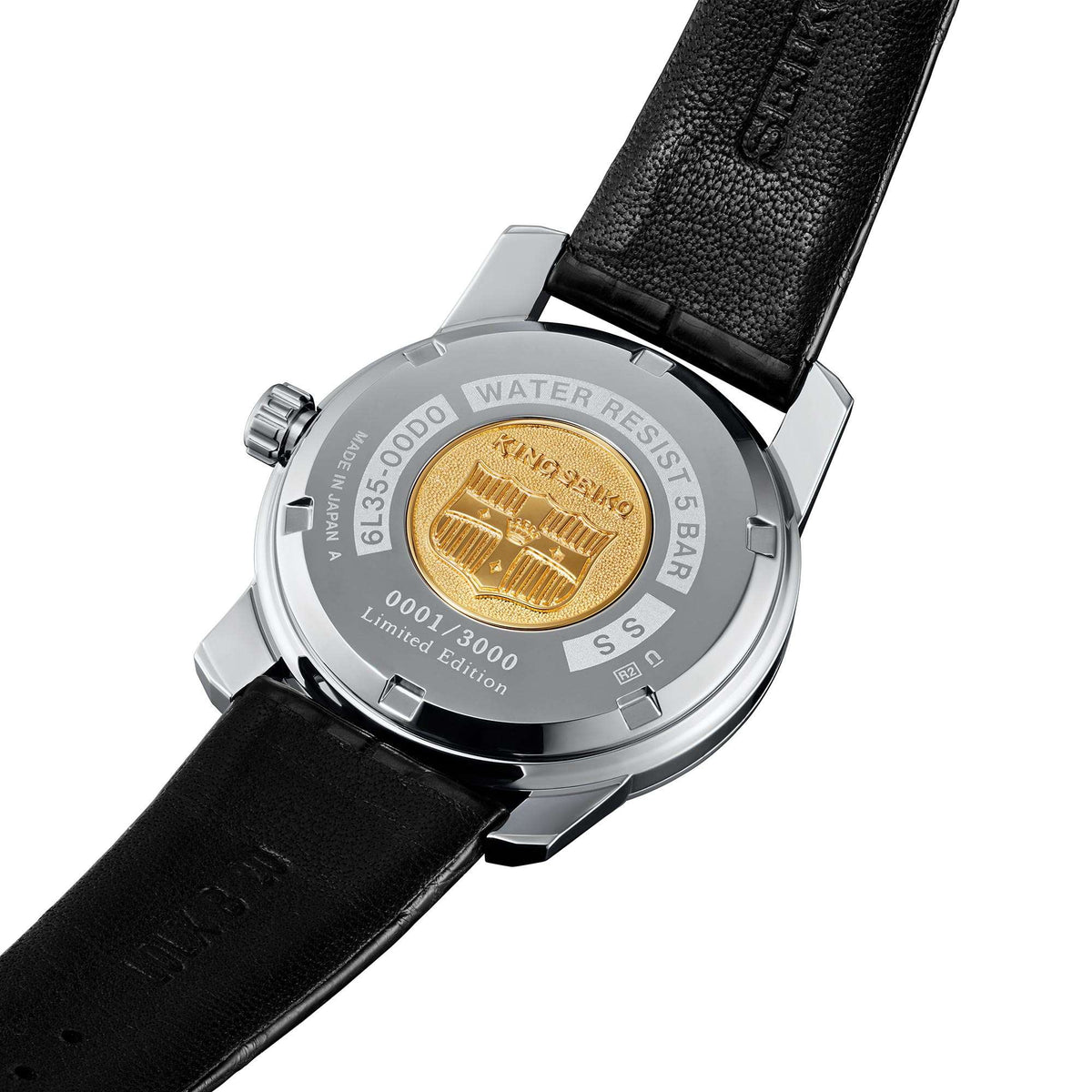 Watch caseback with gold emblem and engraved text, on black leather strap.