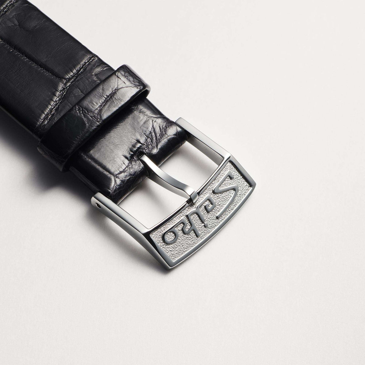 Black leather watch strap with silver buckle clasp and embossed markings.