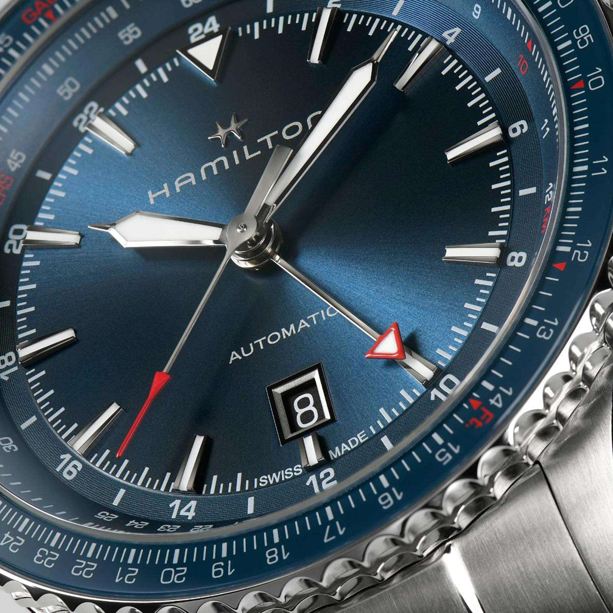 Close-up of men's automatic watch with blue dial, hands, and date window.