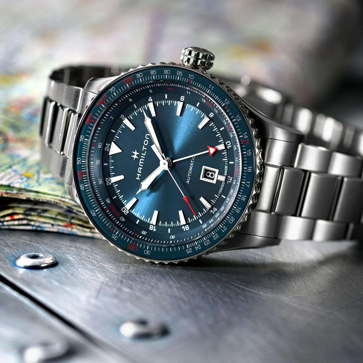 Men's automatic steel watch with blue dial and stainless bracelet on wooden surface.