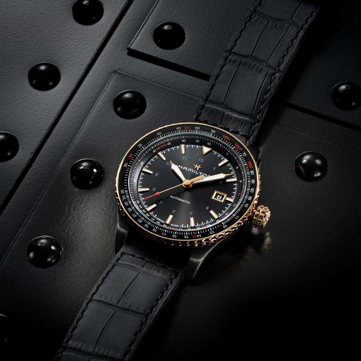 Men's automatic watch with black leather strap, black dial, gold-tone bezel and date window.