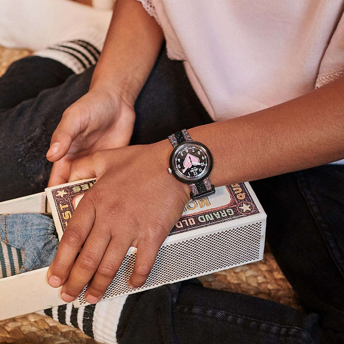 Girls wristwatch on child’s hand, pink heart dial with speckled textile strap