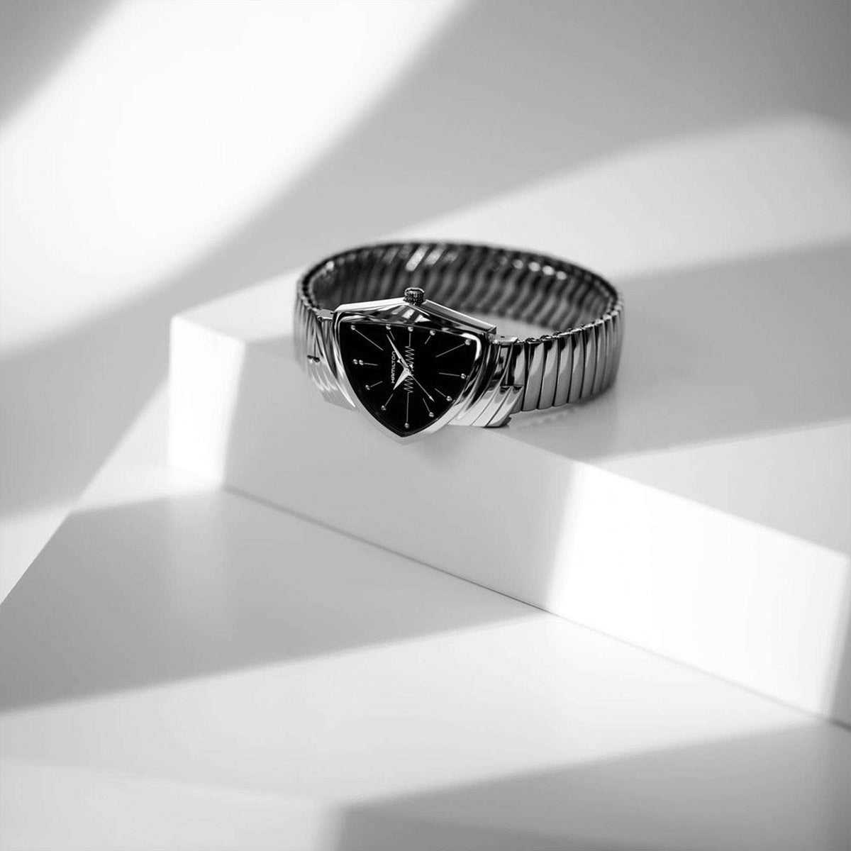 Hamilton Ventura watch resting on a geometric white platform with dramatic light and shadows.