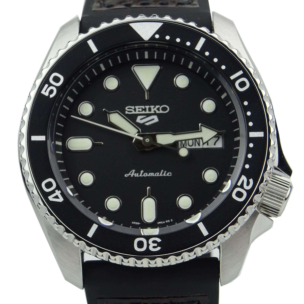 Men's automatic dive watch close-up: black dial, silver bezel, brown leather strap