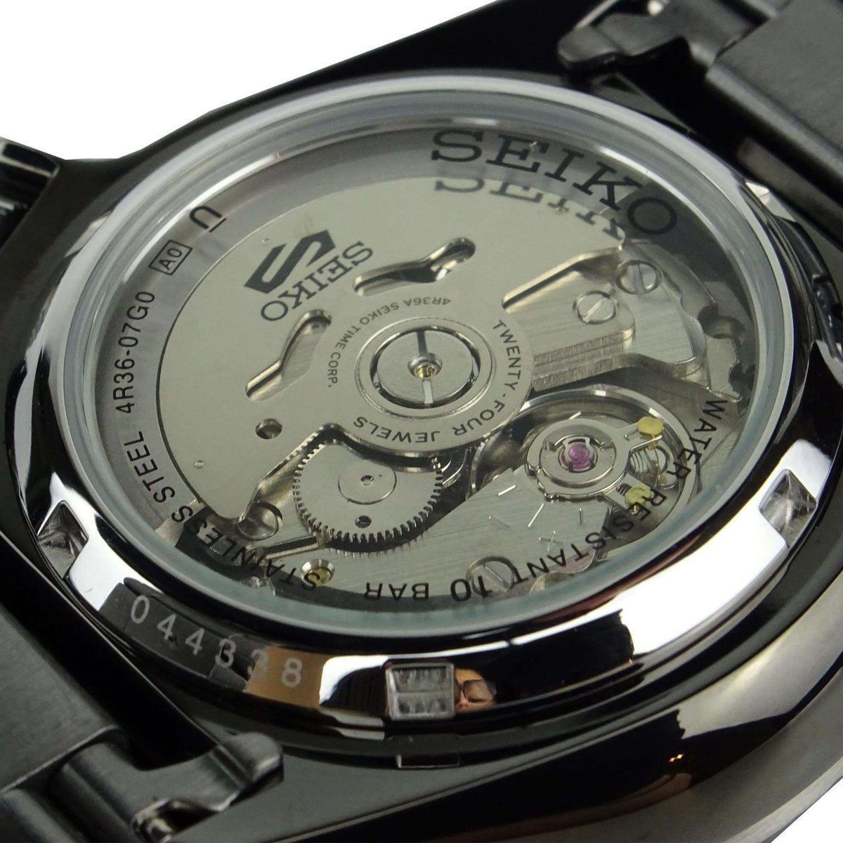 Stainless steel watch caseback with visible mechanical movement and engraved text