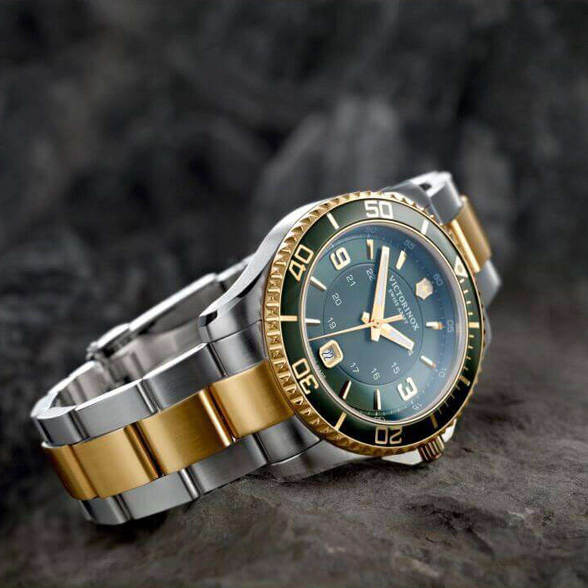 Men's stainless steel quartz watch with dark teal dial, gold bezel, and two-tone bracelet