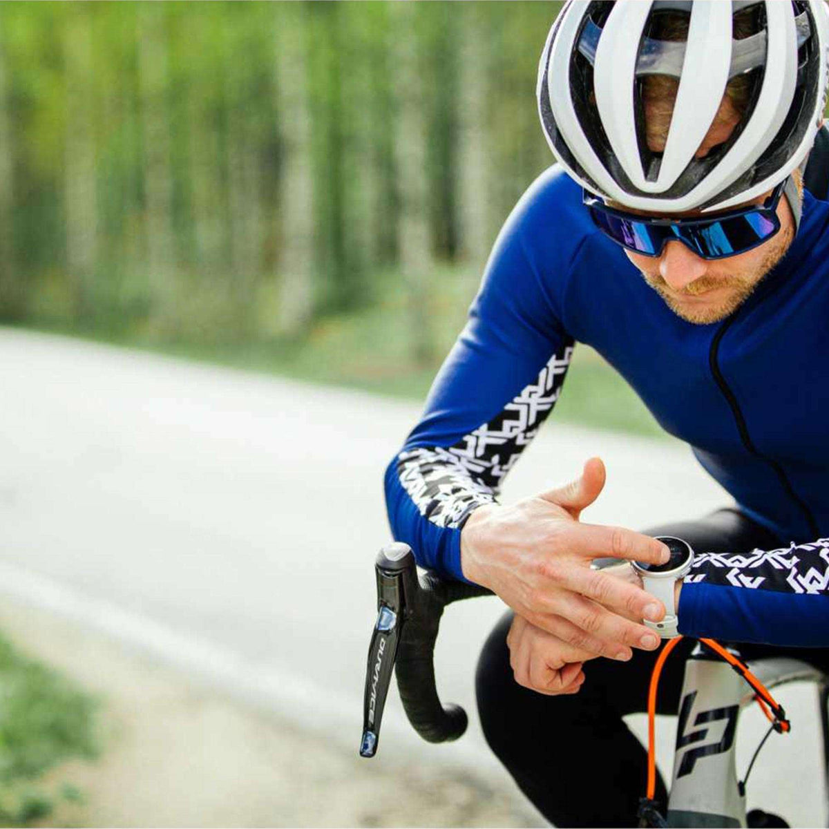 Smartwatch on cyclist's wrist with grey rubber strap and dark display during ride.
