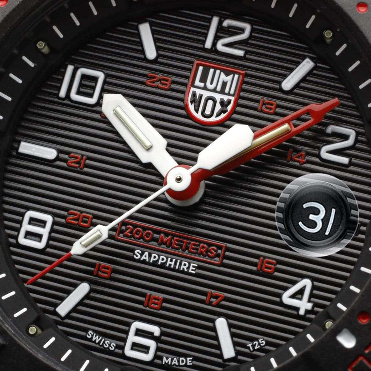 Close-up of black dive watch dial with white markers, red NOx badge, date at 3