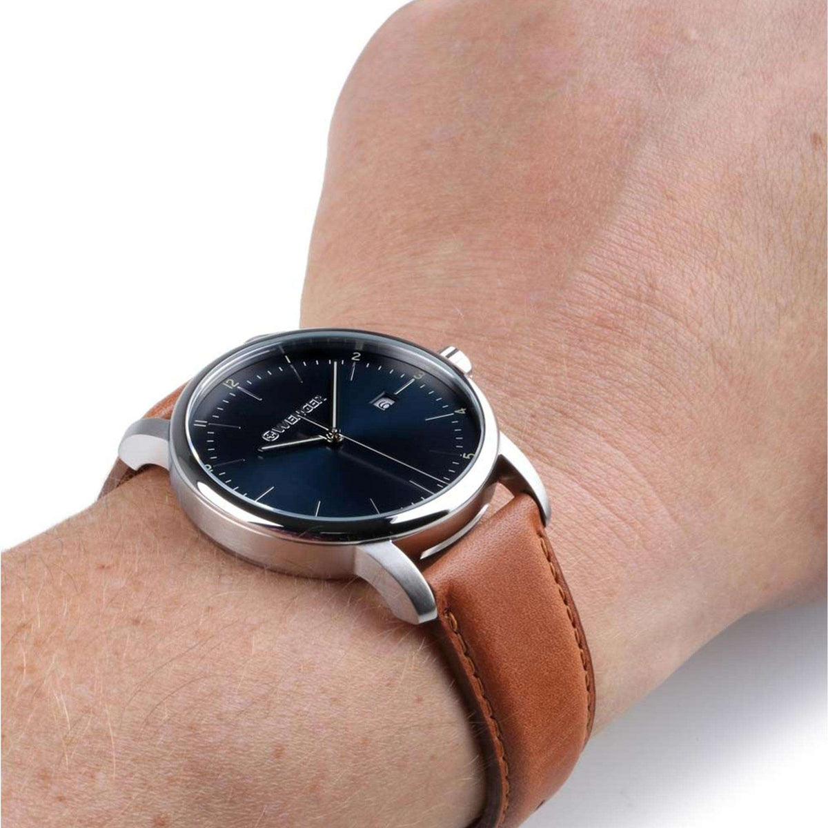 Men's quartz watch on wrist with blue dial and brown leather strap.