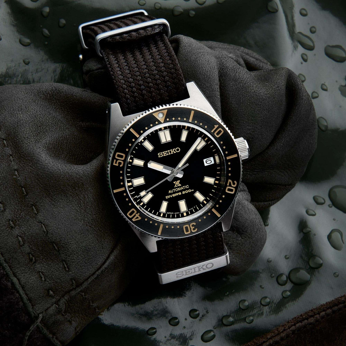 Men's Seiko diver watch on black glove, black dial with gold indices and nylon strap