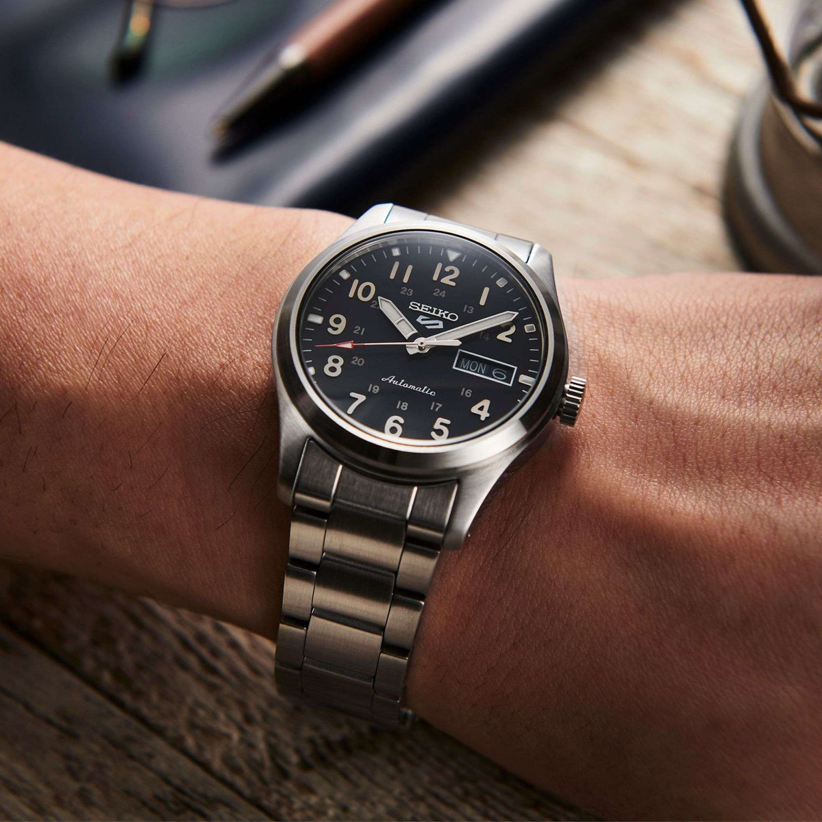 Seiko 5 Sports automatic watch with black dial on wrist, stainless steel bracelet