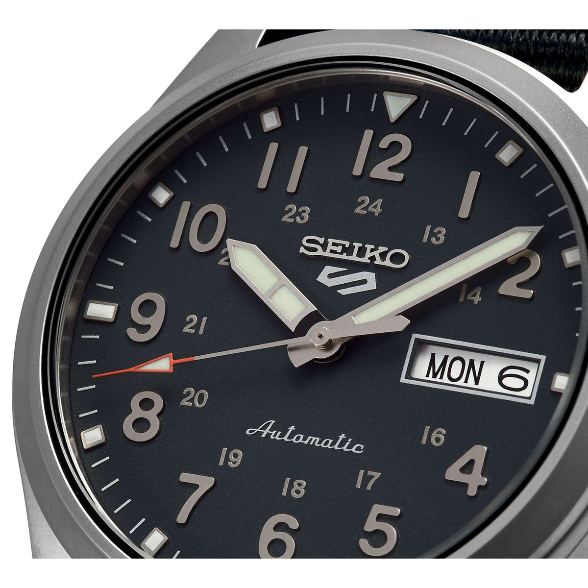 Grey dial field watch close-up with Seiko logo and day/date Monday 6, automatic