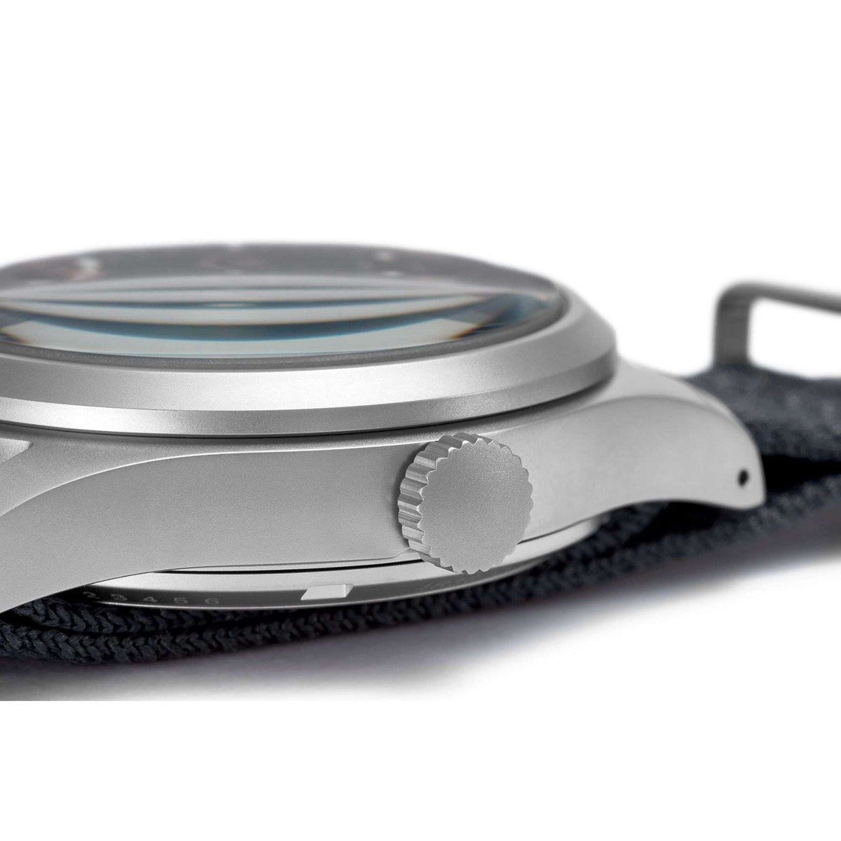 Stainless steel field watch side view with ridged crown and grey NATO strap