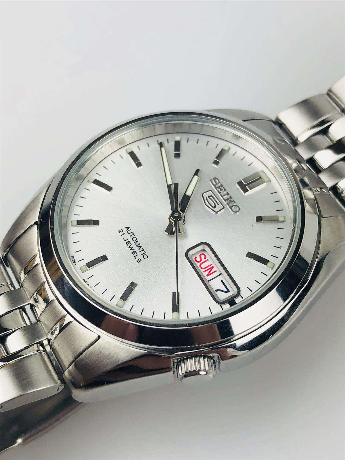 Angled view of Seiko 5 SNK355K1 automatic watch highlighting the silver dial, case and stainless steel bracelet