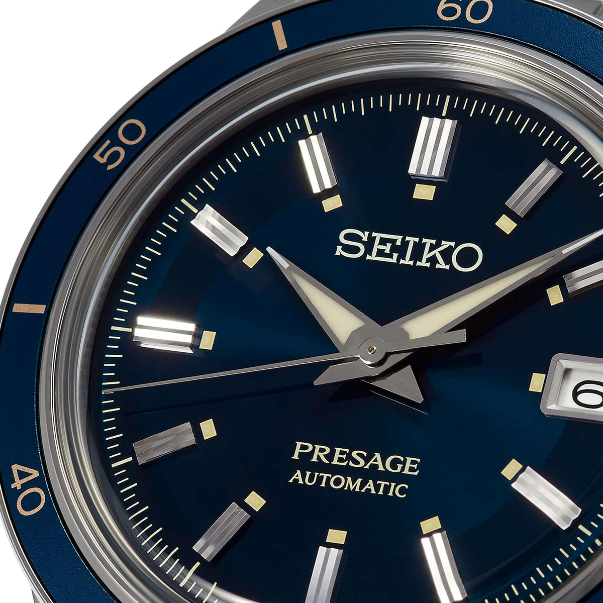 Close-up of men's automatic watch with blue dial, gold-tone hour markers, and date window