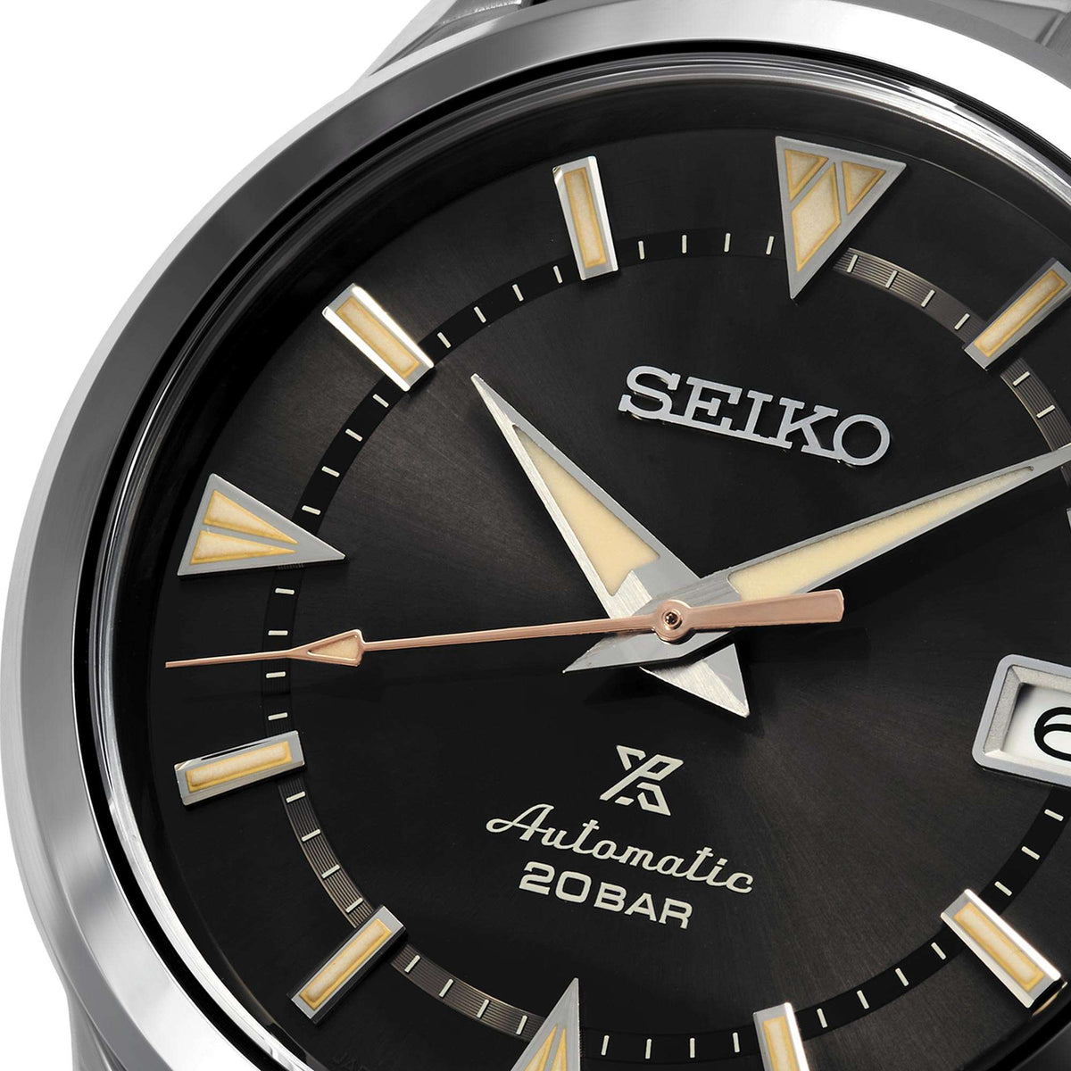 Close-up of automatic watch face: black dial with gold markers, SEIKO logo, date at 3