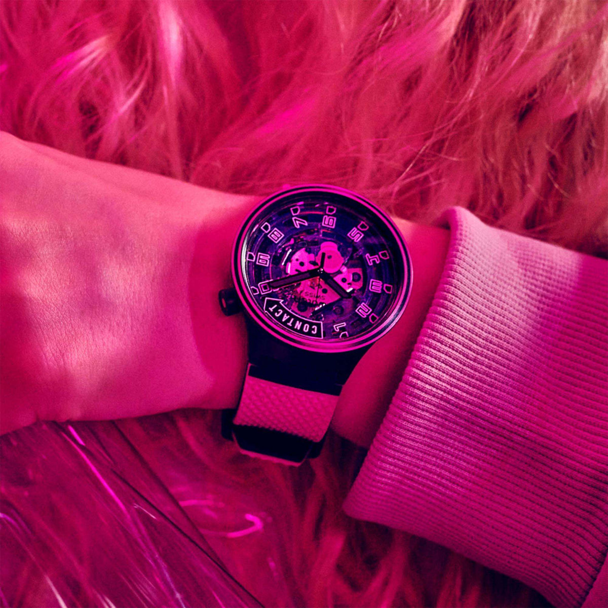 Swatch watch on black silicone strap, neon pink dial and numerals, on wrist