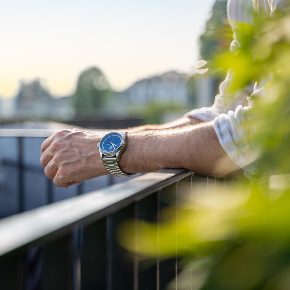 Men's automatic wristwatch on wrist outdoors, blue dial and steel bracelet