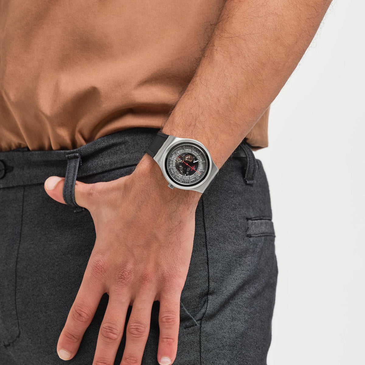 Men’s skeleton watch worn on wrist, silver case, black rubber strap, open dial