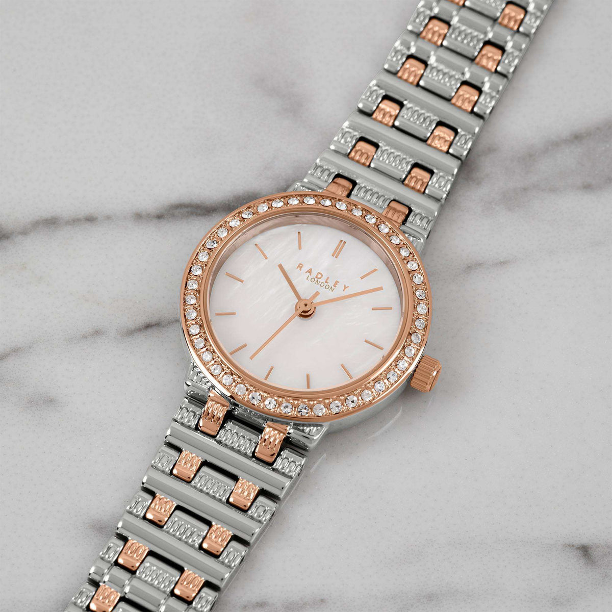 Two-tone quartz watch close-up with mother-of-pearl dial, rose-gold bezel stones