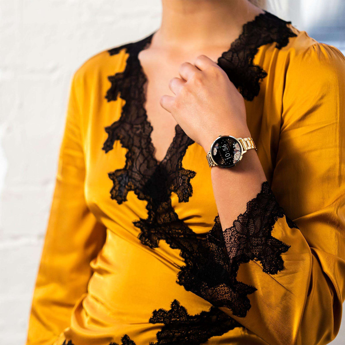 Gold round smartwatch on wrist with black floral face