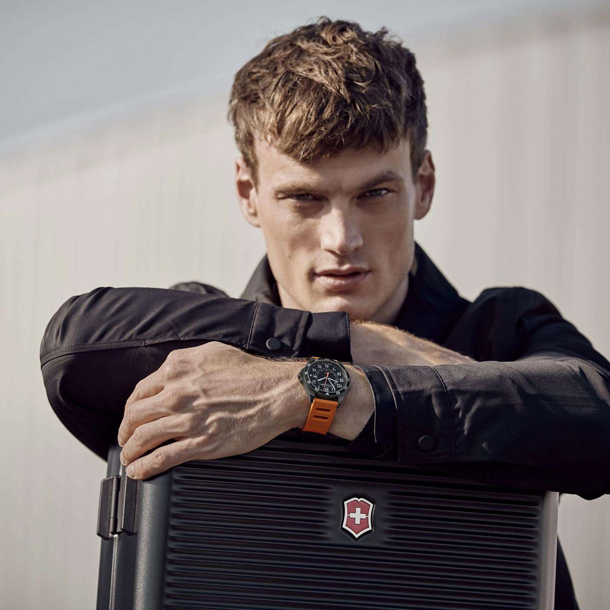 Men's wristwatch on wrist: black dial with orange GMT accents, orange rubber strap.