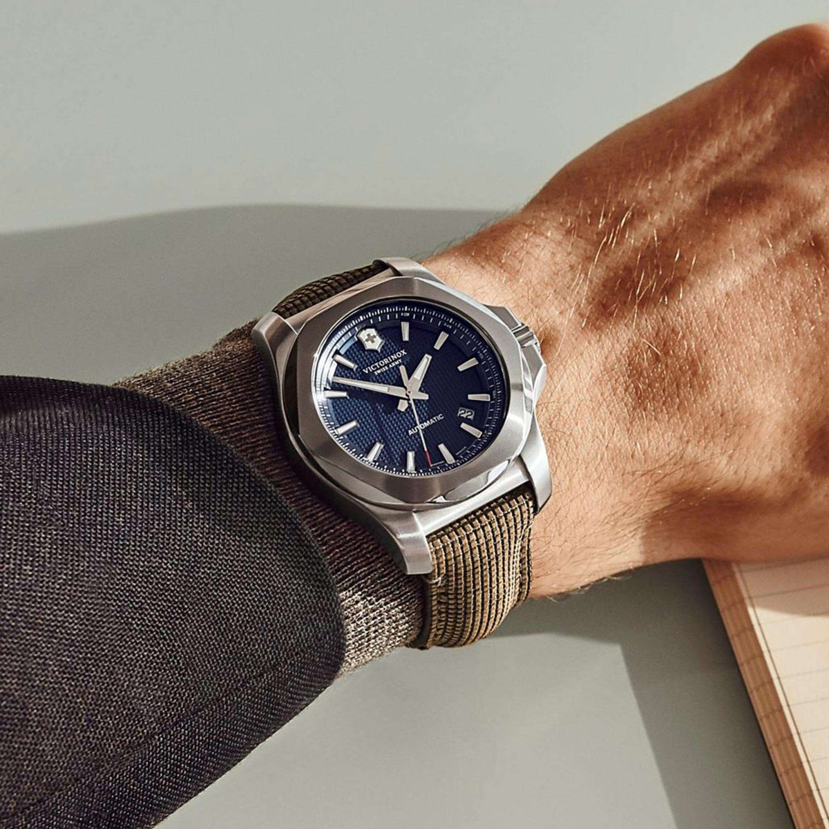 Men's mechanical watch on wrist with blue dial and brown woven strap with steel case
