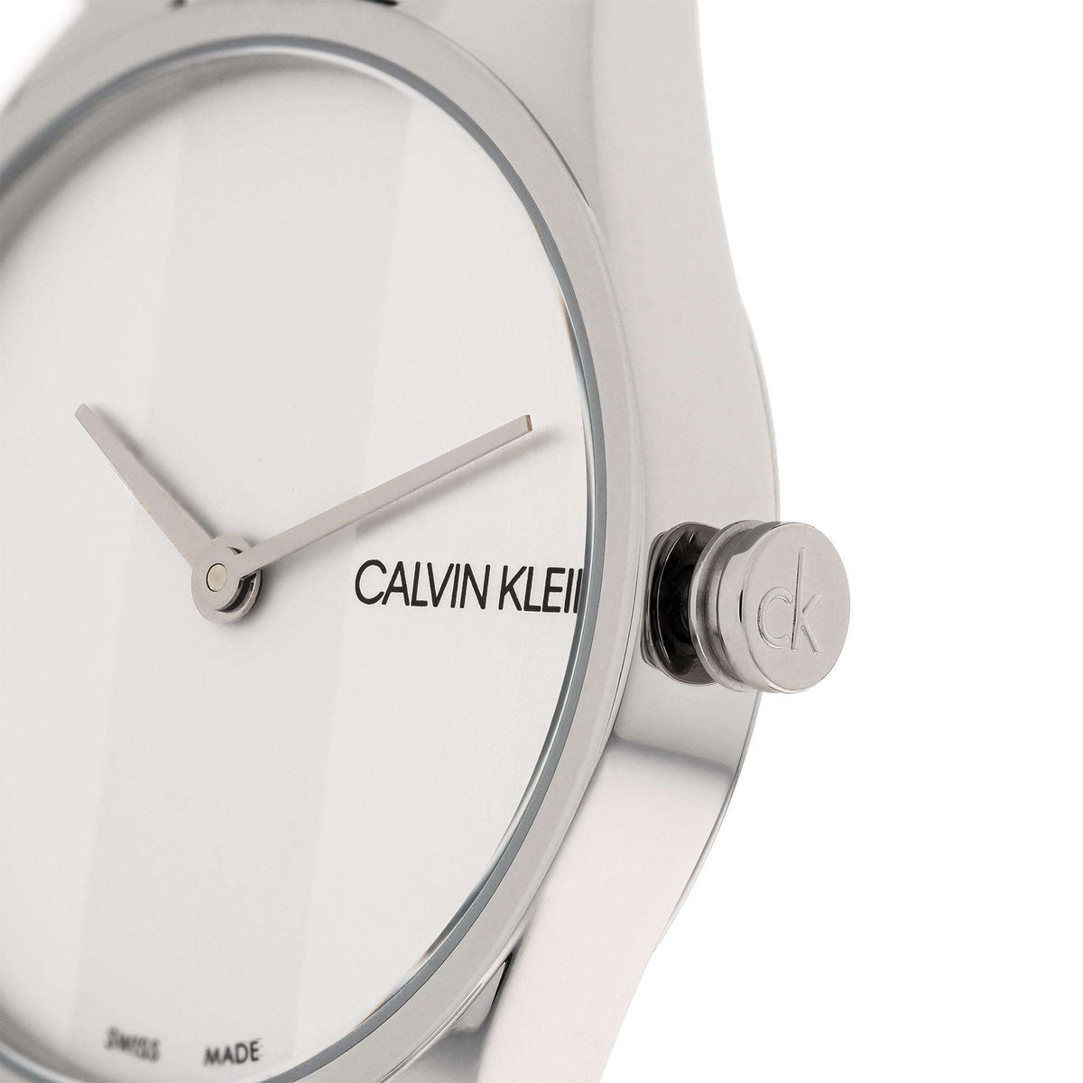 Calvin Klein crown close-up on silver case next to white dial