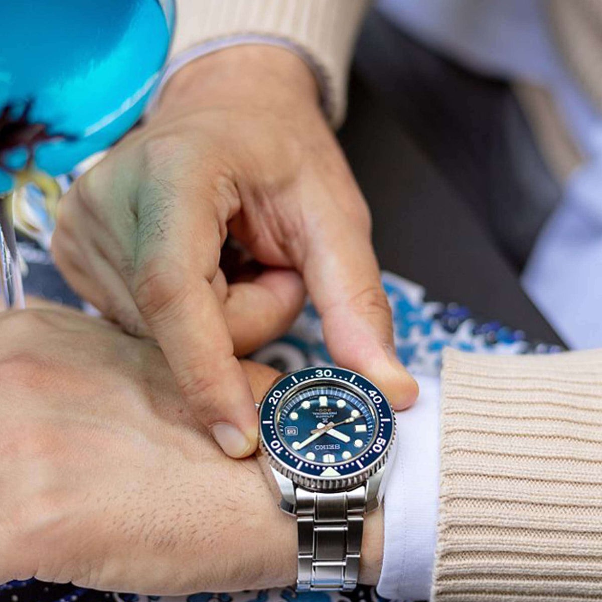 Automatic diver watch with blue dial and stainless steel bracelet worn by a person